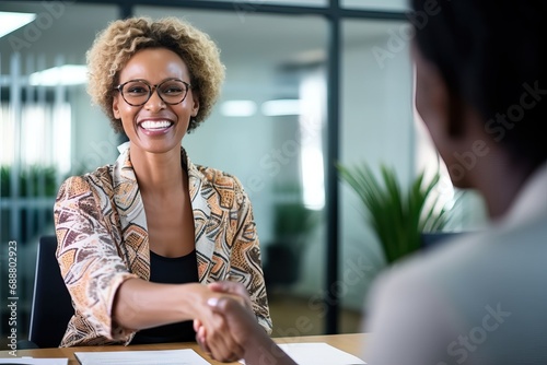 Happy business woman manager handshaking greeting client in office. Smiling female executive making successful deal with partner shaking hand at work standing at meeting table.