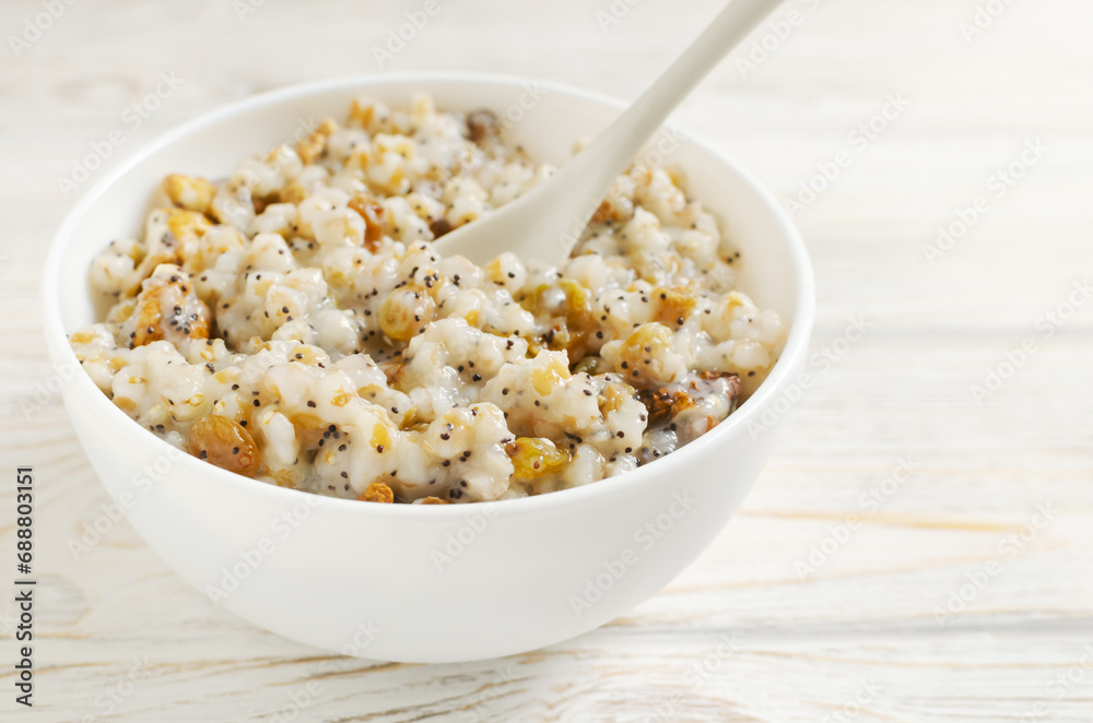 Kutya, a traditional Ukrainian Christmas dish made of wheat groats on the table for Christmas or the old New Year. Boiled porridge with walnuts, raisins, poppy seeds and honey in a white bowl. Kutya, a traditional Ukrainian Christmas dish made of wheat groats on the table for Christmas or the old New Year. Boiled porridge with walnuts, raisins, poppy seeds and honey in a white bowl.