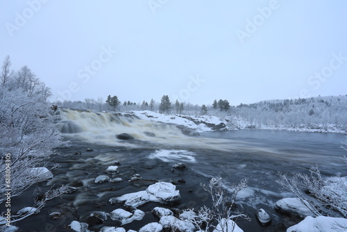 freezing winter waterfall on the background of a snow-covered forest 