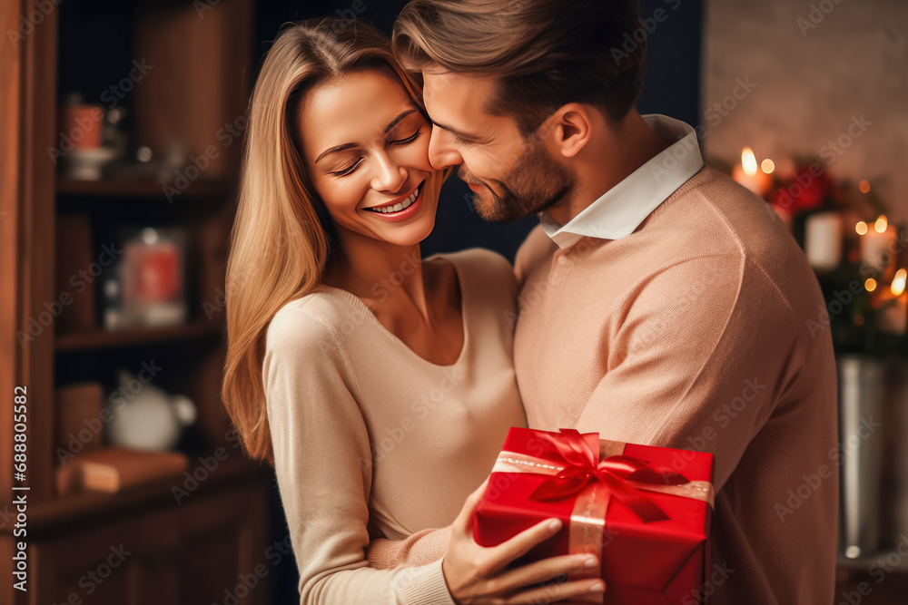 beautiful young couple holding red gift box and smiling at each other beautiful young couple holding red gift box and smiling at each other