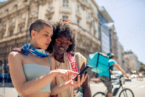 Two diverse young women in city using smartphone photo