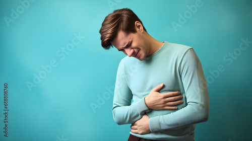 Young man holding his stomach with his hands, experiencing pain in his abdominal region, medical and health care problem concept, adult person belly inflammation, gastritis symptoms  photo