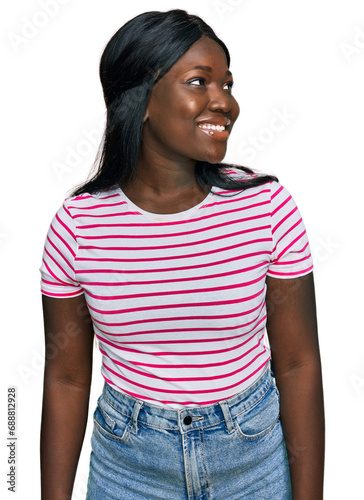 African young woman wearing casual striped t shirt looking away to side with smile on face, natural expression. laughing confident.
