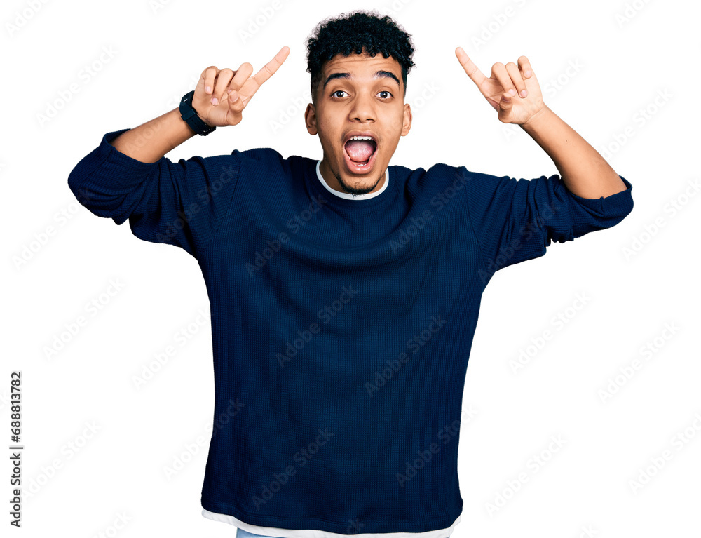Young african american man wearing casual clothes smiling amazed and surprised and pointing up with fingers and raised arms. Young african american man wearing casual clothes smiling amazed and surprised and pointing up with fingers and raised arms.