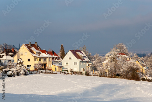 Beautiful winter in a European village - view of a snow-covered field against the backdrop of country houses