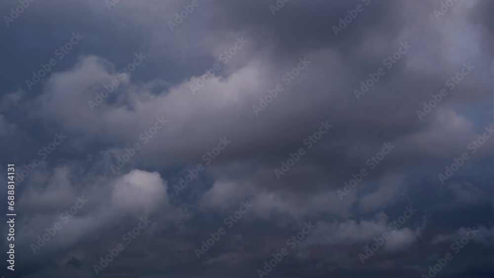 Close-up of fluffy, white and dark blue tropical storm clouds moving slowly around. Magnificent dramatic nature on a windy autumn morning. Relaxing or meditative, continuously changing cloudscapes.
