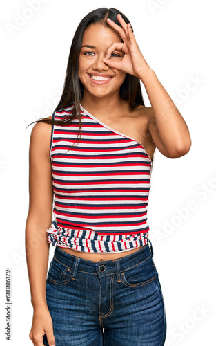 Beautiful hispanic woman wearing casual clothes doing ok gesture with hand smiling, eye looking through fingers with happy face.