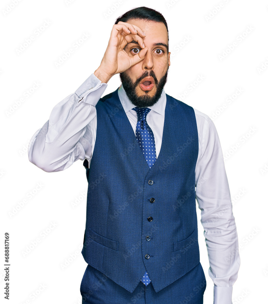 Young man with beard wearing business vest doing ok gesture shocked with surprised face, eye looking through fingers. unbelieving expression. Young man with beard wearing business vest doing ok gesture shocked with surprised face, eye looking through fingers. unbelieving expression.