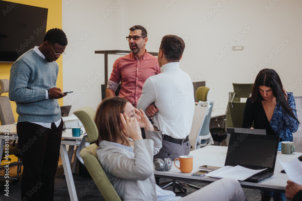 Obraz premium Young, female employee struggling severe headaches caused of migraine during working hours with her coworkers at modern office.