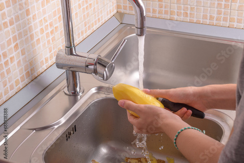Female hands washing a peeling potato with hand under running water in sink in the kitchenVegetables, vegetarian, preparation for cooking, healthy food, food lifestyle photo