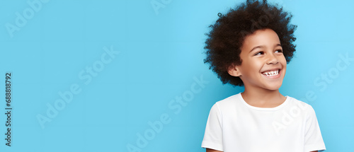 happy latin boy with afro hair on a blue background - copy space © Jess rodriguez