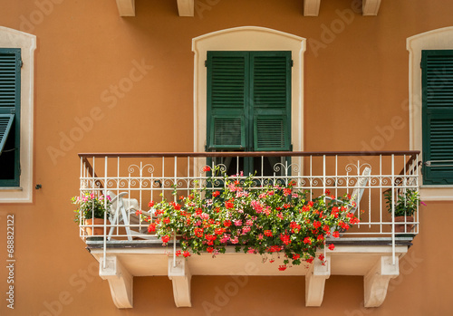 balcony with geranium flowers on a terracotta facade with traditional Italian...