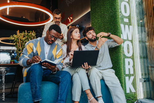 A diverse team of confident professionals collaborates in a co-working space. They work together on a new project  gathering data and solving problems.