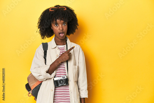 Teen girl with backpack, camera, ready for vacation pointing to the side