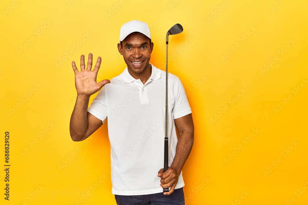 African American man golfer, yellow studio backdrop, smiling cheerful showing number five with fingers.