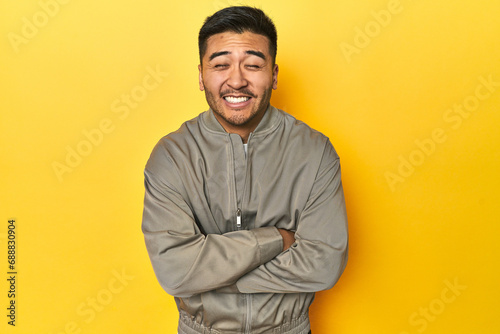 Stylish Asian man in gray jacket on yellow studio laughing and having fun. © Asier