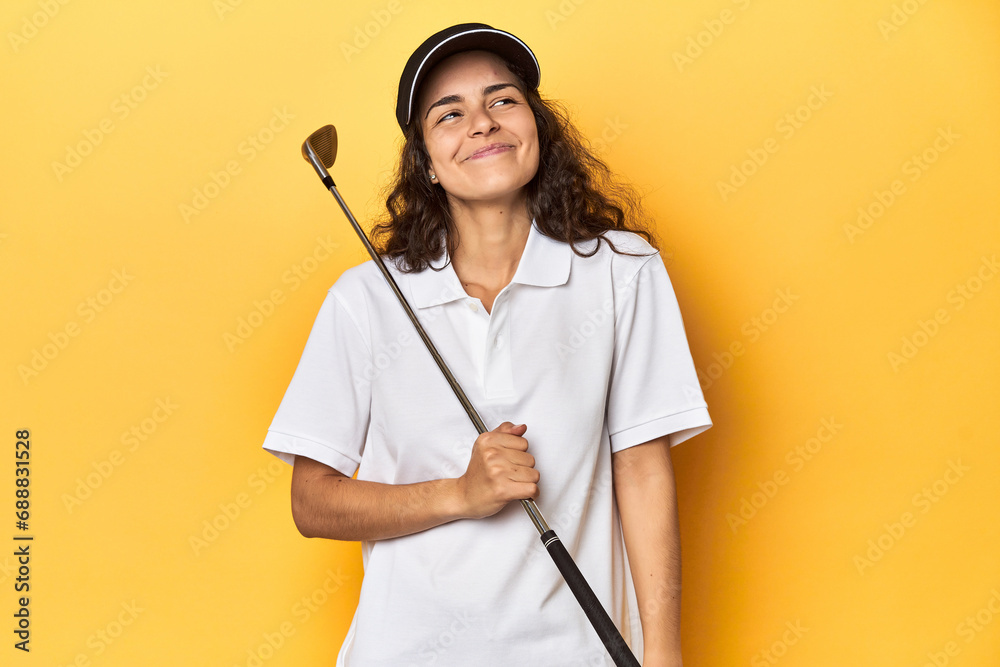 Golfer woman with cap, golf polo, yellow studio, dreaming of achieving goals and purposes Golfer woman with cap, golf polo, yellow studio, dreaming of achieving goals and purposes