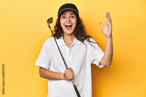Golfer woman with cap, golf polo, yellow studio, receiving a pleasant surprise, excited and raising hands.