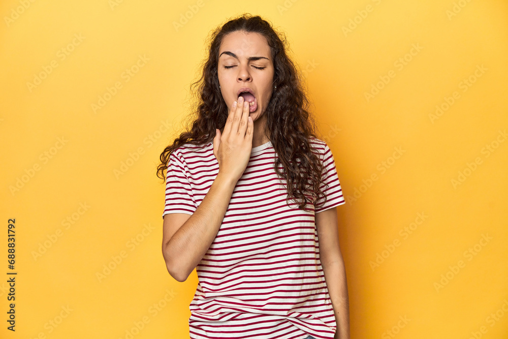 Young Caucasian woman, yellow studio background, yawning showing a tired gesture covering mouth with hand. Young Caucasian woman, yellow studio background, yawning showing a tired gesture covering mouth with hand.