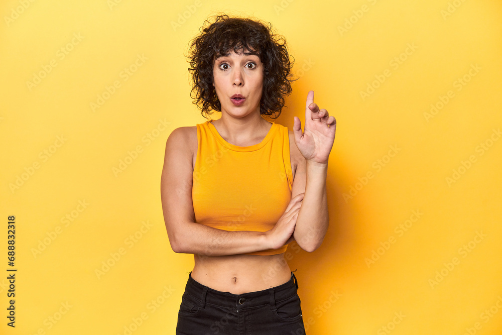 Curly-haired Caucasian woman in yellow top having some great idea, concept of creativity. Curly-haired Caucasian woman in yellow top having some great idea, concept of creativity.