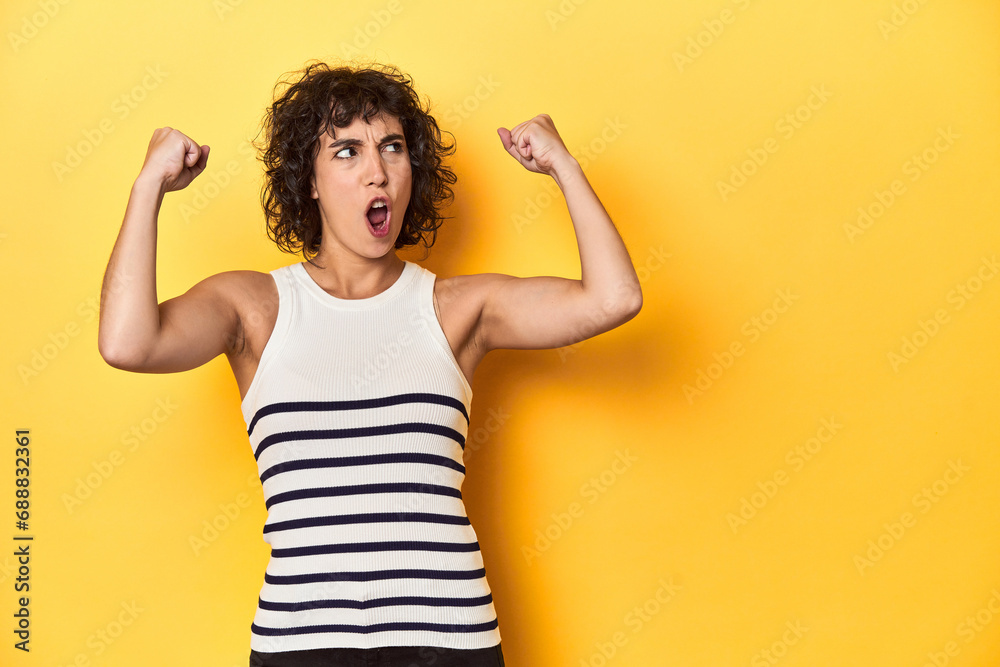 Caucasian curly-haired woman in white tank-top raising fist after a victory, winner concept. Caucasian curly-haired woman in white tank-top raising fist after a victory, winner concept.