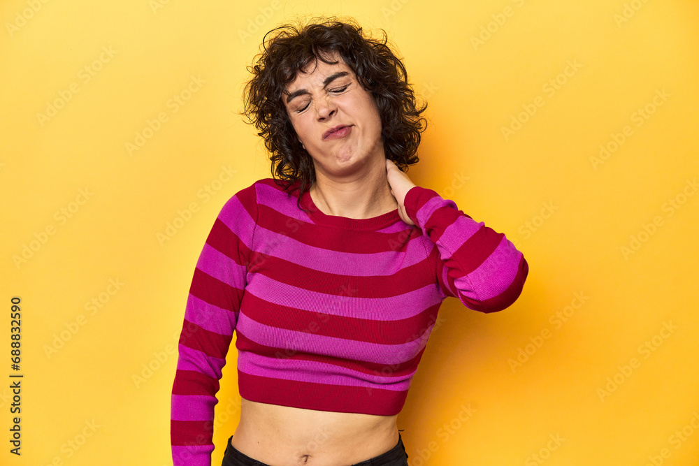 Caucasian curly-haired woman in pink striped-top suffering neck pain due to sedentary lifestyle. Caucasian curly-haired woman in pink striped-top suffering neck pain due to sedentary lifestyle.