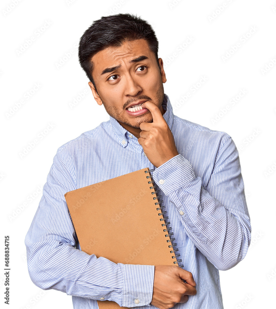 Chinese student with a notebook in studio relaxed thinking about something looking at a copy space. Chinese student with a notebook in studio relaxed thinking about something looking at a copy space.