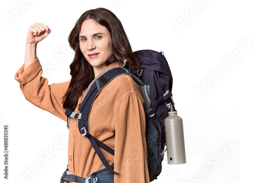 Young Caucasian with hiking gear and bottle raising fist after a victory, winner concept.