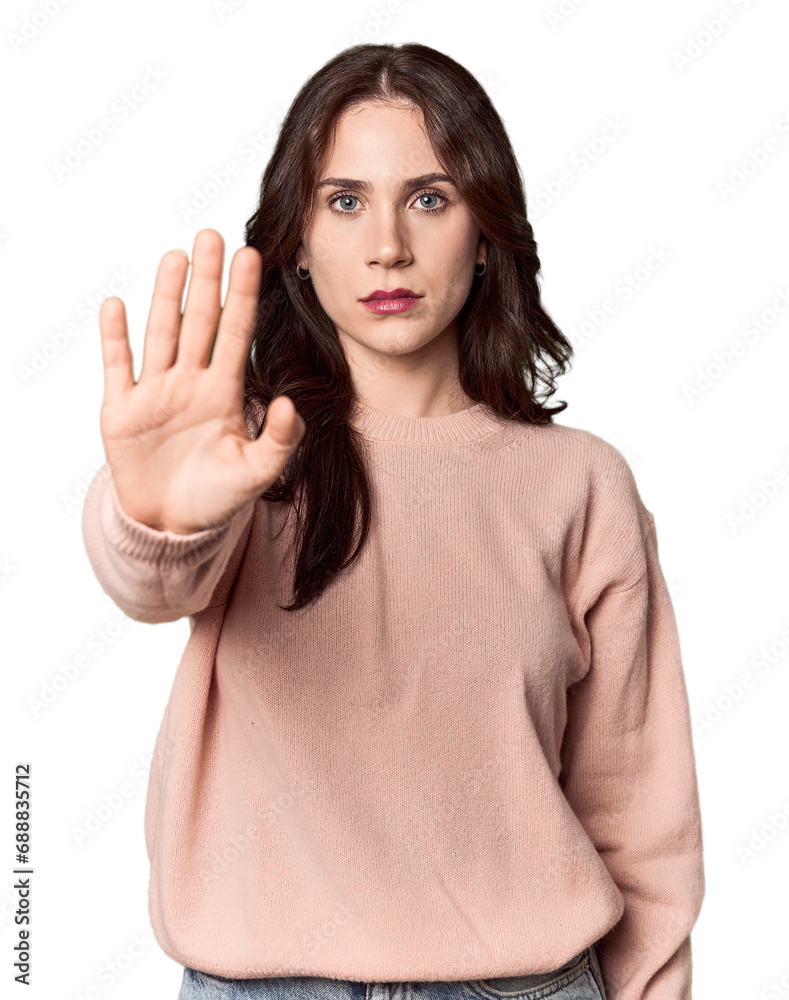 Young Caucasian woman in a studio setting standing with outstretched hand showing stop sign, preventing you. Young Caucasian woman in a studio setting standing with outstretched hand showing stop sign, preventing you.