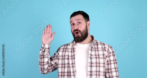 Young handsome bearded man wearing casual waiving saying hello happy and smiling, friendly welcome gesture on blue background.