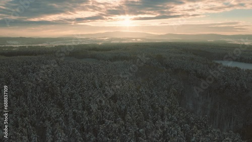 Aerial drone flight over snow covered forest in winter, cold weather, peaceful relaxing view during sunset or sunrise