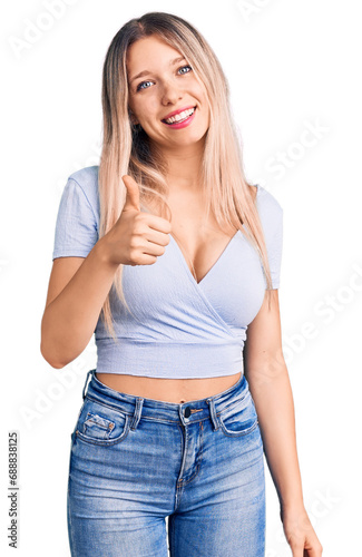 Young beautiful blonde woman wearing casual clothes doing happy thumbs up gesture with hand. approving expression looking at the camera showing success.