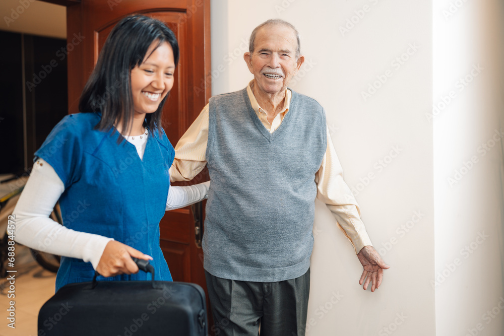 Obraz premium Happy old man visited by a nurse at home
