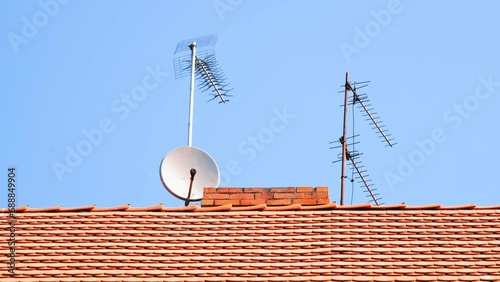 Digital TV Aerial Antenna and Satellite Dish Mounted on Top of Building Red Tiles Roof photo