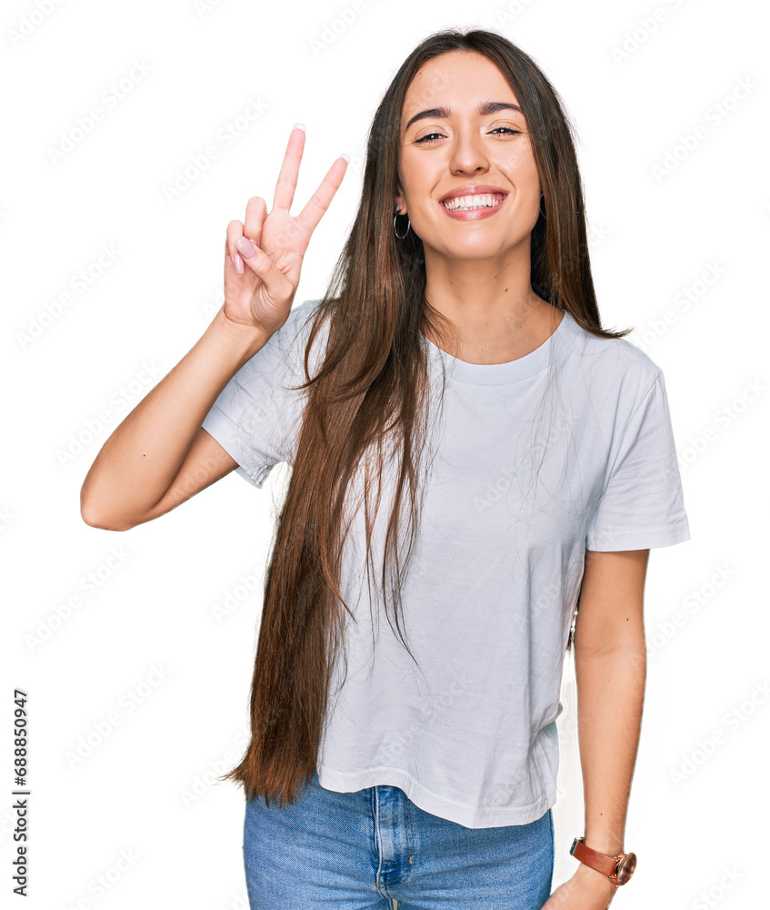 Young hispanic girl wearing casual white t shirt showing and pointing up with fingers number two while smiling confident and happy. Young hispanic girl wearing casual white t shirt showing and pointing up with fingers number two while smiling confident and happy.