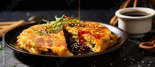 Kimchi pancake with soy dipping sauce, a Korean dish, being eaten on a plate.
