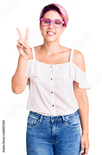 Young beautiful woman with pink hair wearing casual clothes and glasses showing and pointing up with fingers number two while smiling confident and happy.