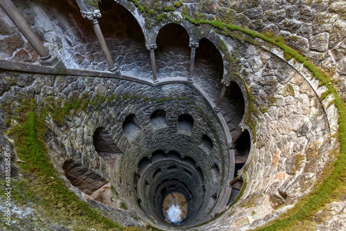 The ceremonial Initiation Well and spiral staircase into the underground tunnel system seen from the ground level at the Quinta da Regaleira Palace in Sintra, Portugal.
