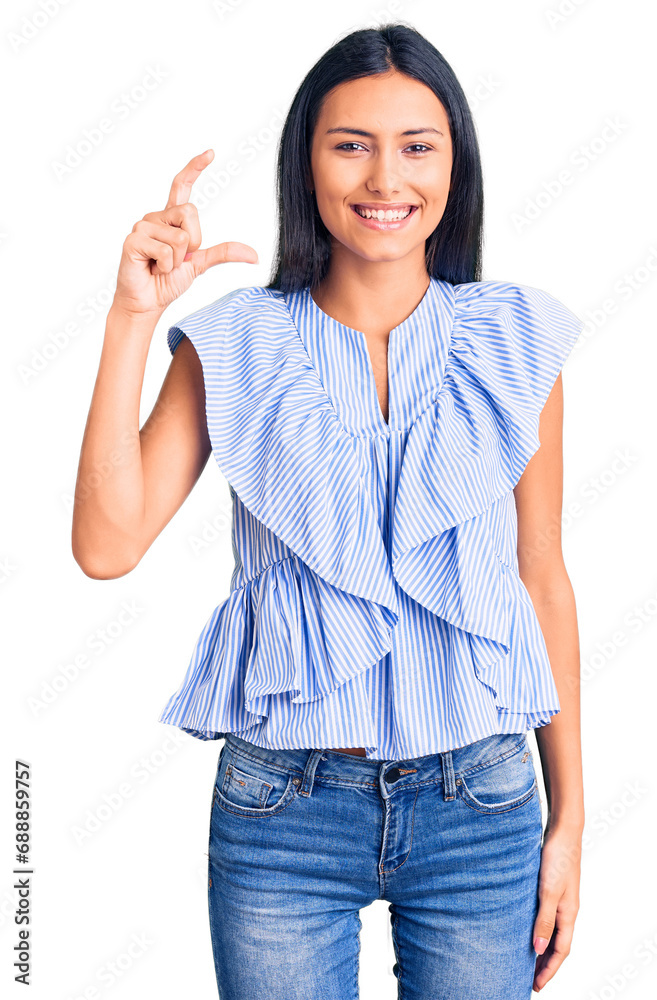 Young beautiful latin girl wearing casual clothes smiling and confident gesturing with hand doing small size sign with fingers looking and the camera. measure concept. Young beautiful latin girl wearing casual clothes smiling and confident gesturing with hand doing small size sign with fingers looking and the camera. measure concept.