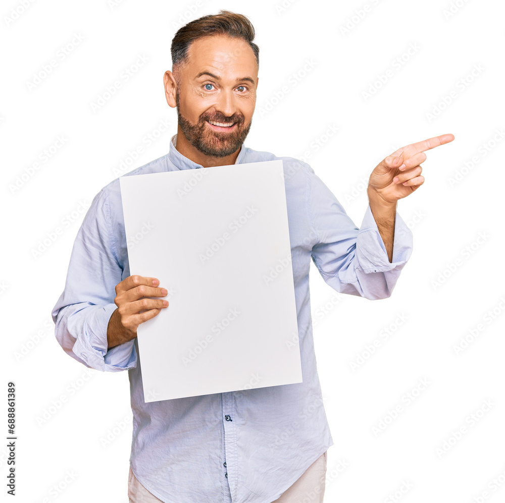 Handsome middle age man holding blank empty banner smiling happy pointing with hand and finger to the side Handsome middle age man holding blank empty banner smiling happy pointing with hand and finger to the side