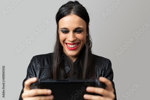 A young woman, with red lipstick, laughs happily as she plays with a handheld video game console she holds in her hands photo