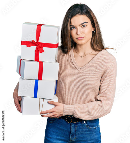 Young caucasian girl holding gifts relaxed with serious expression on face. simple and natural looking at the camera.