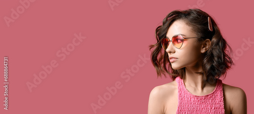 Beautiful young woman with curly hair on pink background with space for text photo