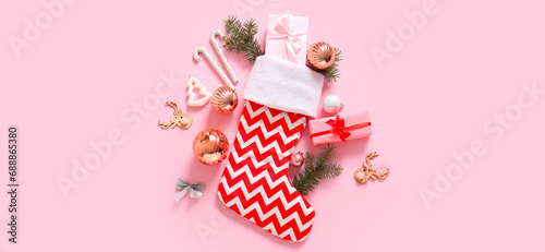 Beautiful Christmas sock with gifts and decorations on pink background
