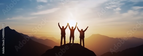 Celebrate victory and success over sunset background, Together overcoming obstacles as a group of three people raising hands up on the top of a mountain. photo