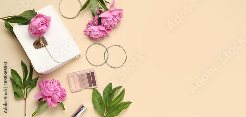 Stylish female handbag, bracelets, eyeshadows and beautiful peony flowers on beige background with space for text
