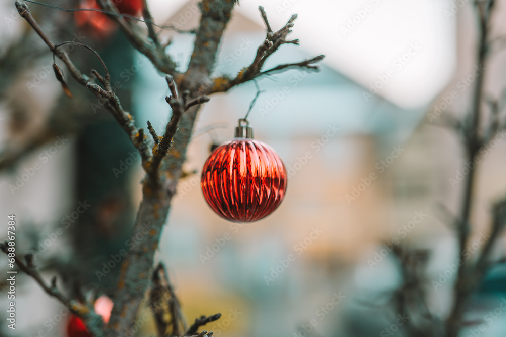 Obraz premium Red Christmas balls on tree branches on winter city streets. Soft focus. Christmas in Europe.Christmas season in Europe. Winter holiday decor 
