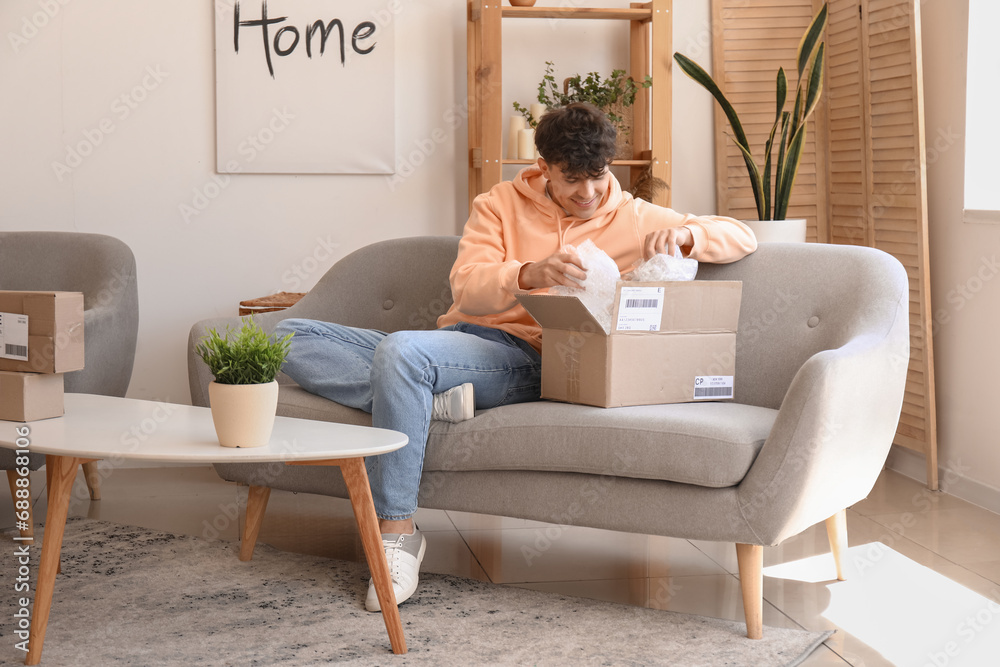 Young man opening parcel at home Young man opening parcel at home