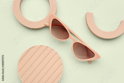 Plaster podiums with stylish sunglasses on green background, closeup