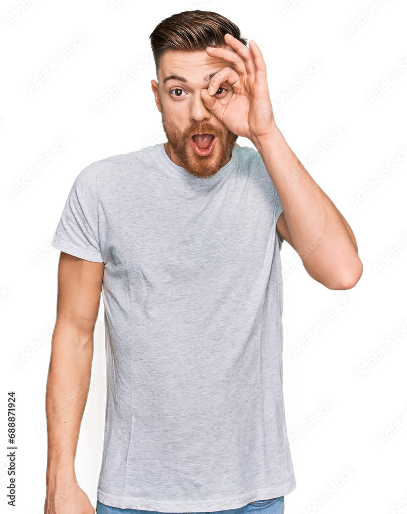 Young redhead man wearing casual grey t shirt doing ok gesture shocked with surprised face, eye looking through fingers. unbelieving expression. Young redhead man wearing casual grey t shirt doing ok gesture shocked with surprised face, eye looking through fingers. unbelieving expression.